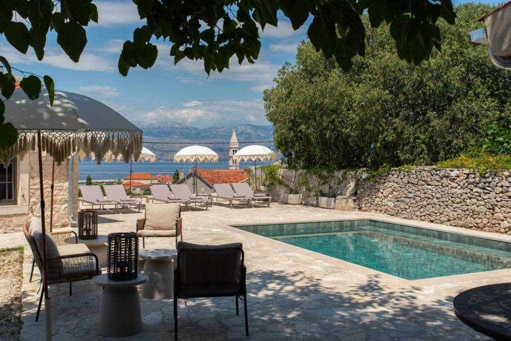 a swimming pool with chairs and a table and a pool at Doma in Supetar
