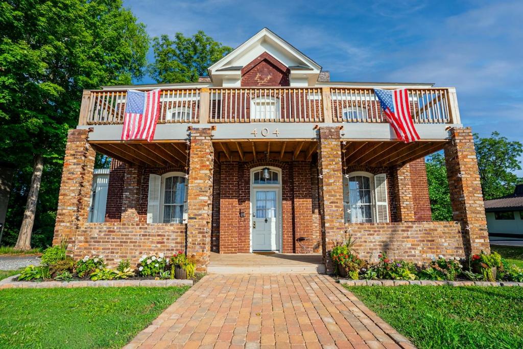 a brick house with a balcony with two american flags at Cozy House with Private Sauna in Maryville