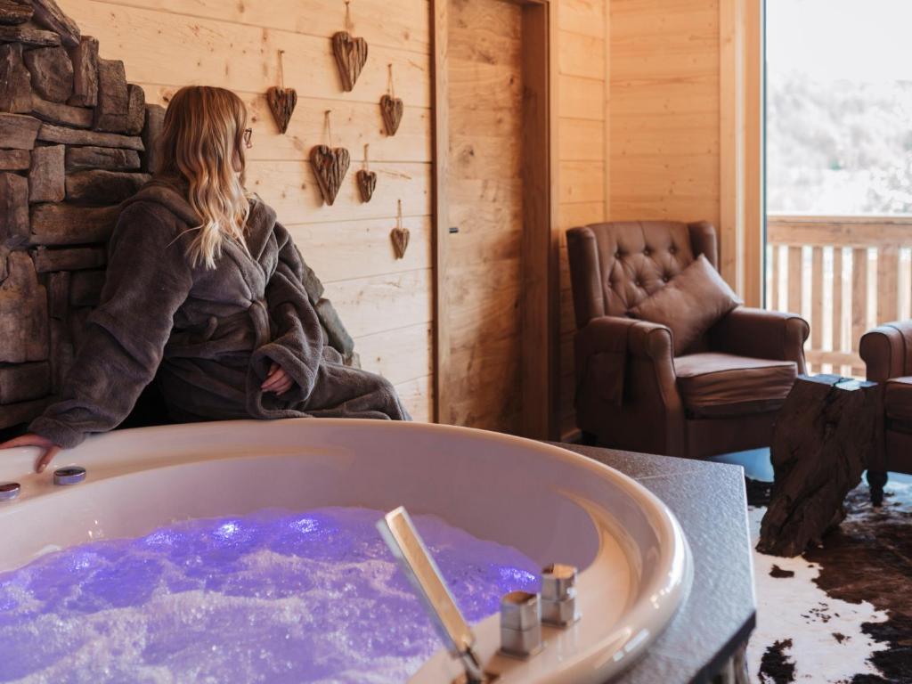 a woman sitting in a tub in a room at Romantikchalet Bärenhöhle mit eigenen Wellnessbereich, Komfort und viel Ruhe in Vorra