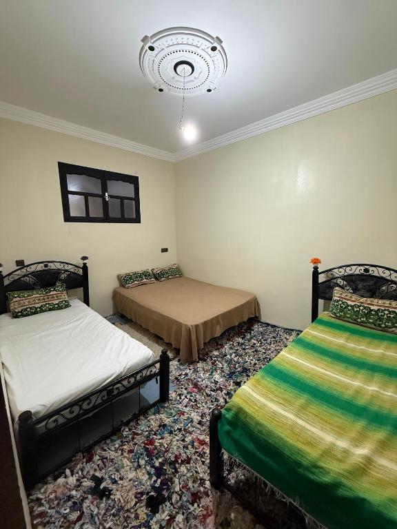 a bedroom with two beds and a chandelier at Gite Souran Imsker in Tagadirt Aït Ali