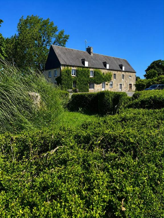 a house on top of a hill with bushes at Ferme La Hougue B&B in Coigny
