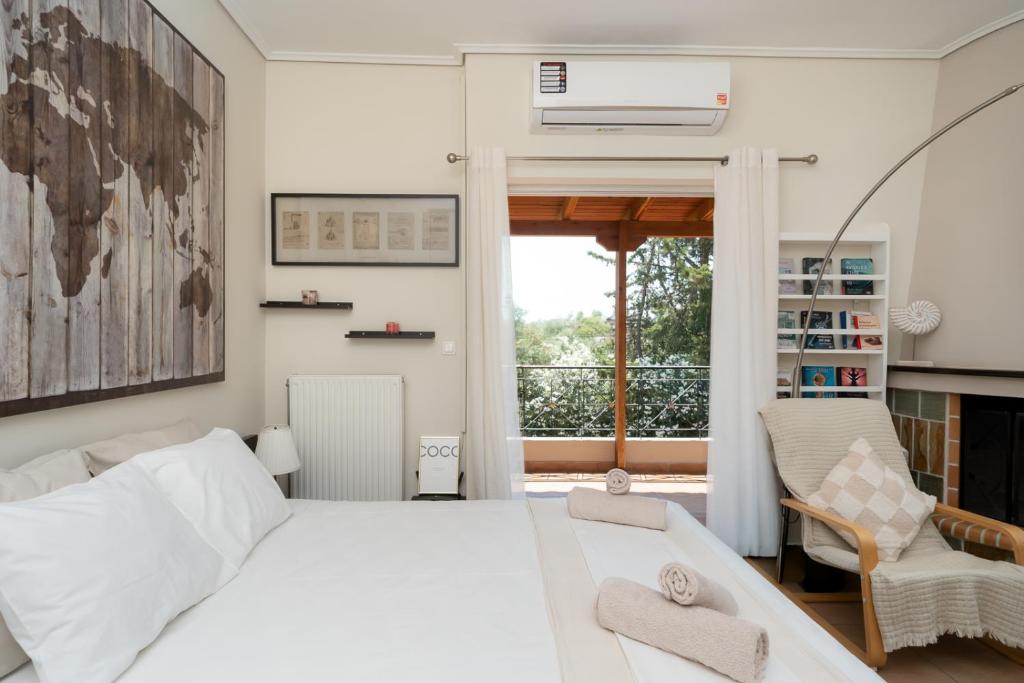 a white bedroom with a bed and a chair at Naria Home by A&D Properties in Porto Rafti
