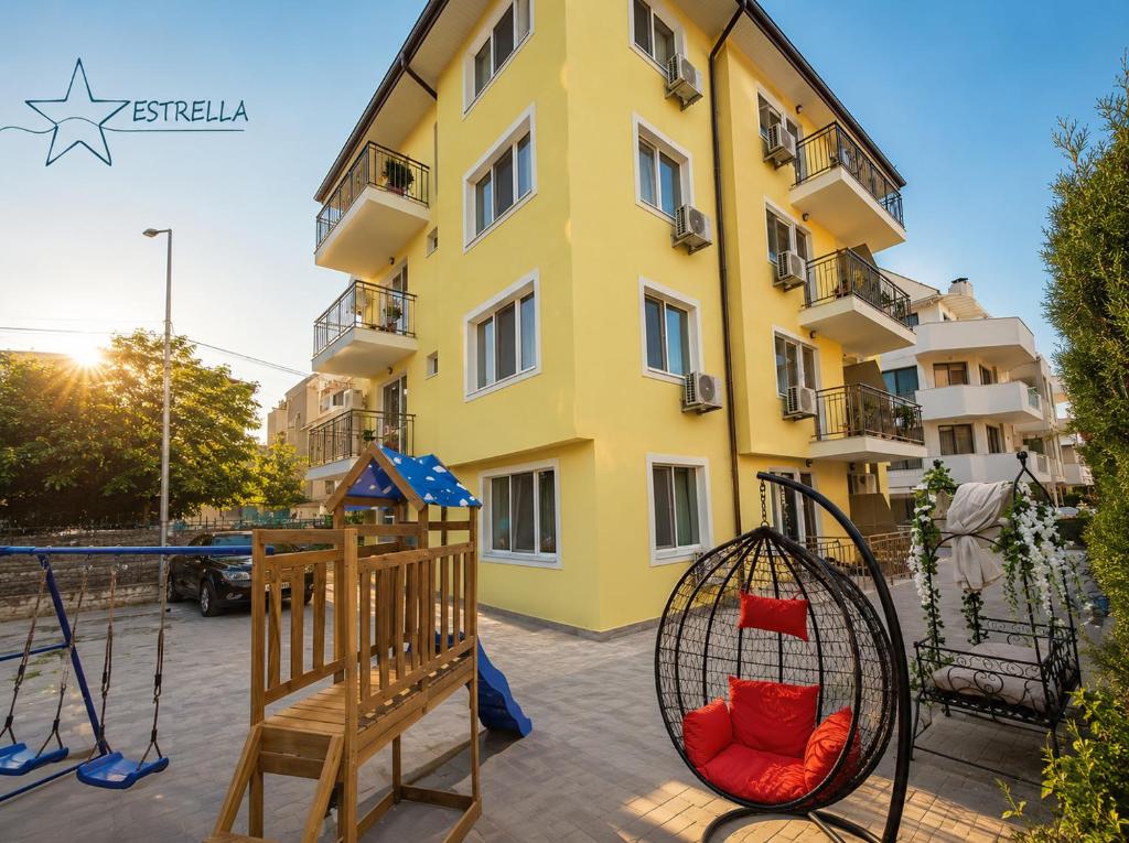 a property with a playground in front of a building at Естрела къща за гости in Ravda