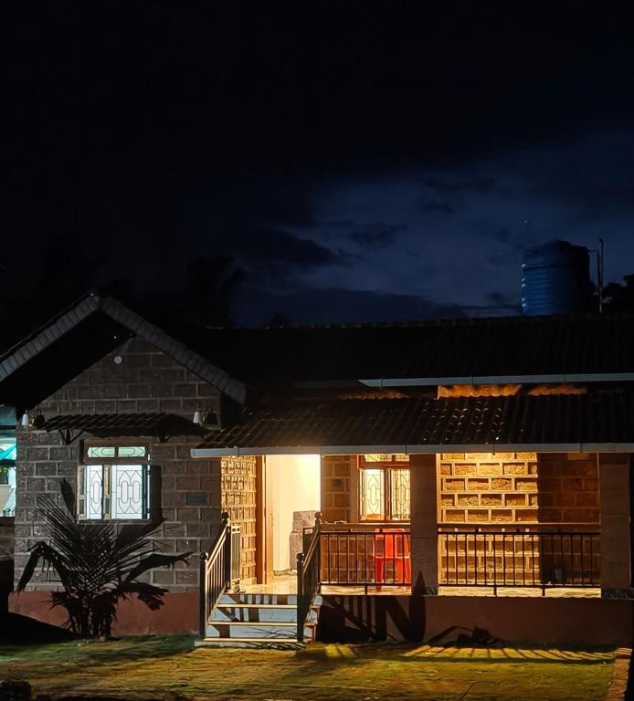 a brick house with a porch and a deck at night at Farmview Guest House Netravali in Netorlim