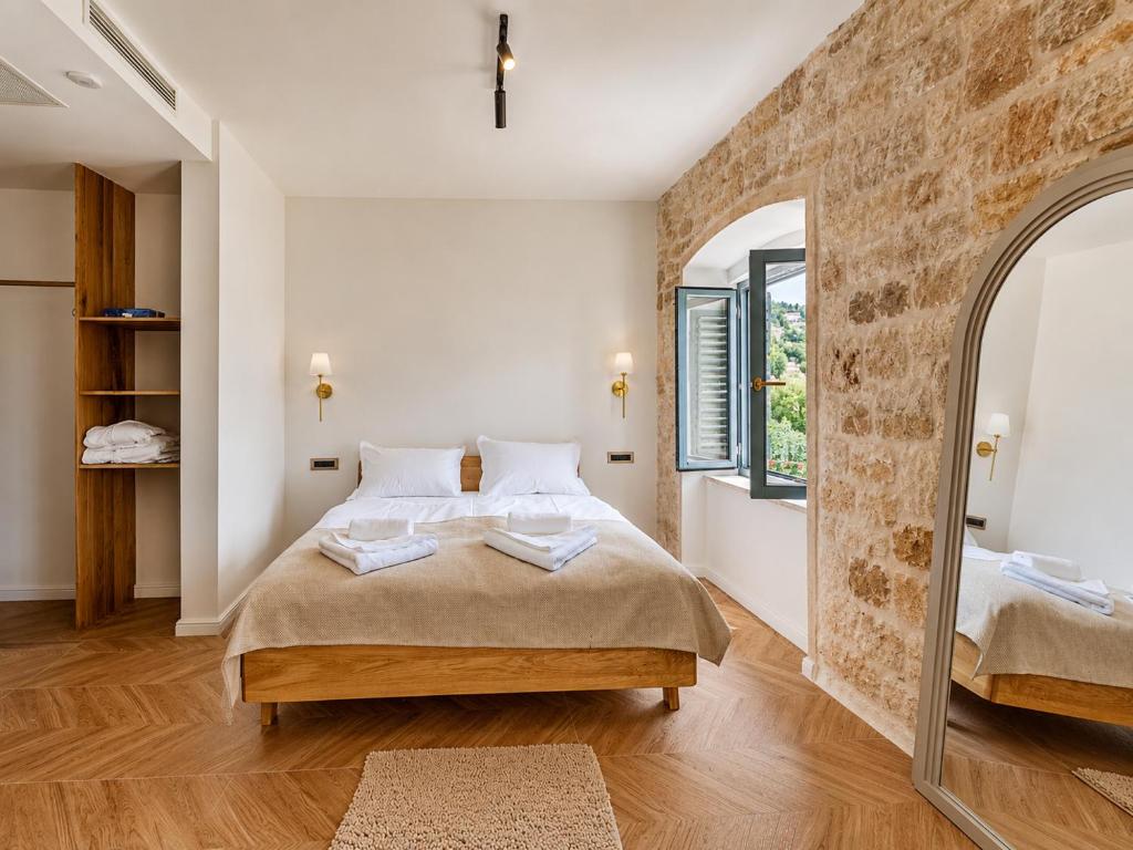 a bedroom with a large bed and a stone wall at Hotel Heritage Casa Blanka in Makarska