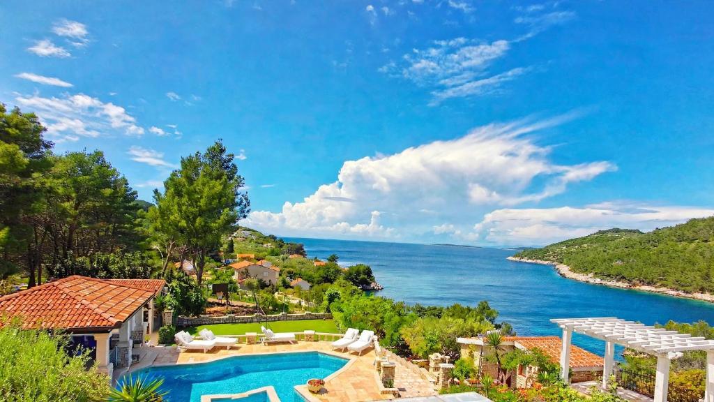 a house with a swimming pool and a view of the water at Villa Stone House Poplat in Vela Luka