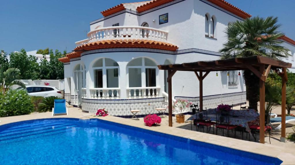 a villa with a swimming pool in front of a house at casa Costa Dorada in Les tres Cales