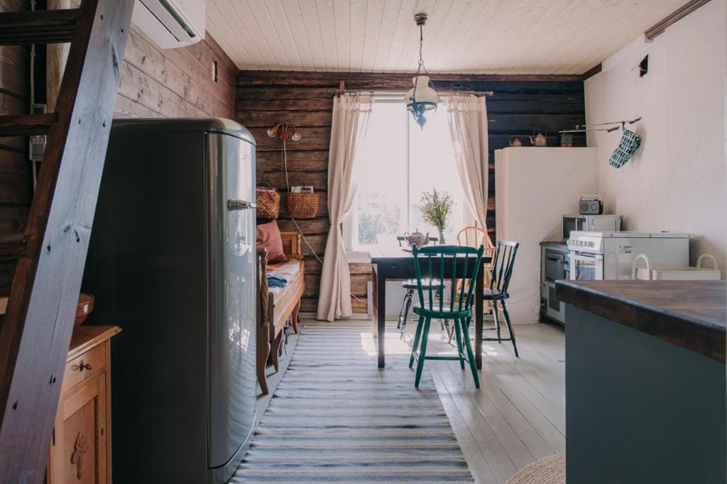 a kitchen and dining room with a table and a refrigerator at Cozy forest cabin with wood-fired sauna in Naantali