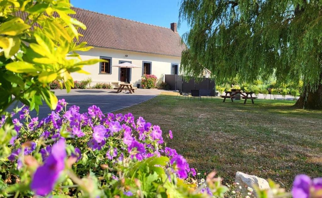a house with purple flowers in front of a yard at La Ferme Des Pierrettes in Menneville