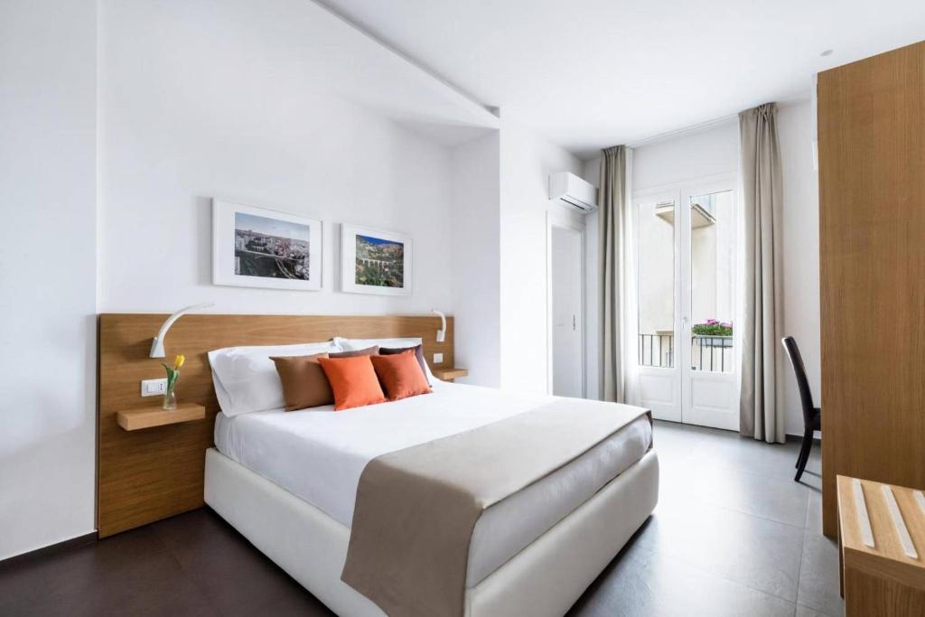 a bedroom with a large white bed with orange pillows at Aurà Guest House Iblea in Ragusa
