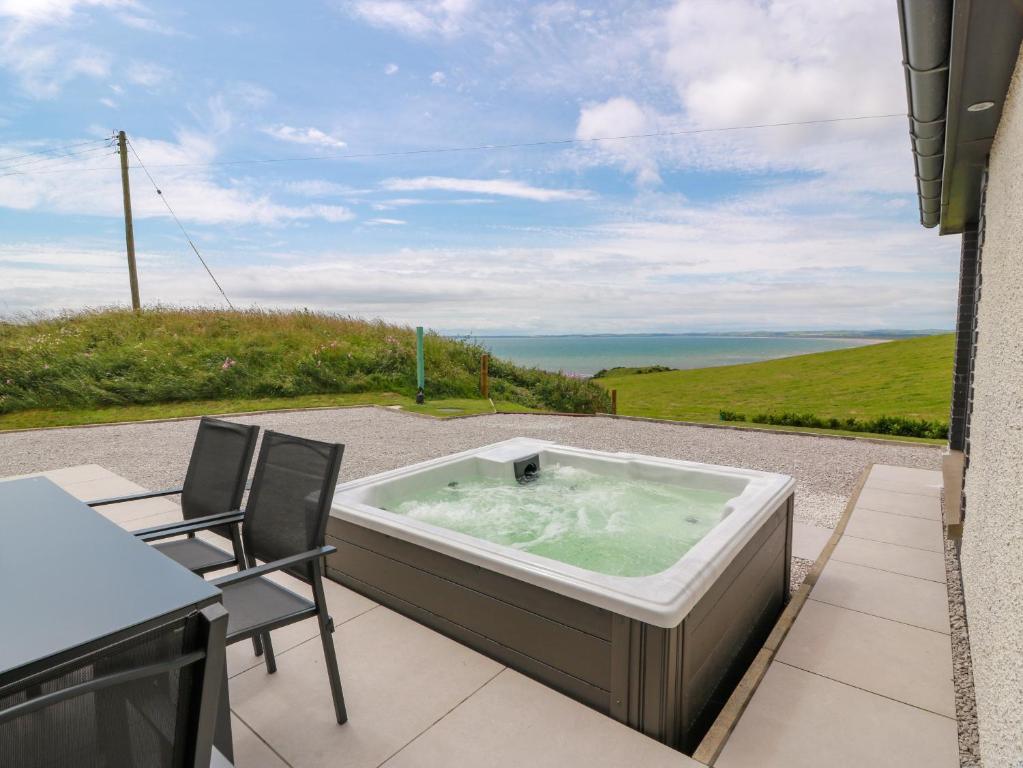 a hot tub on a patio with a table and chairs at Balcarry Barn in Newton Stewart