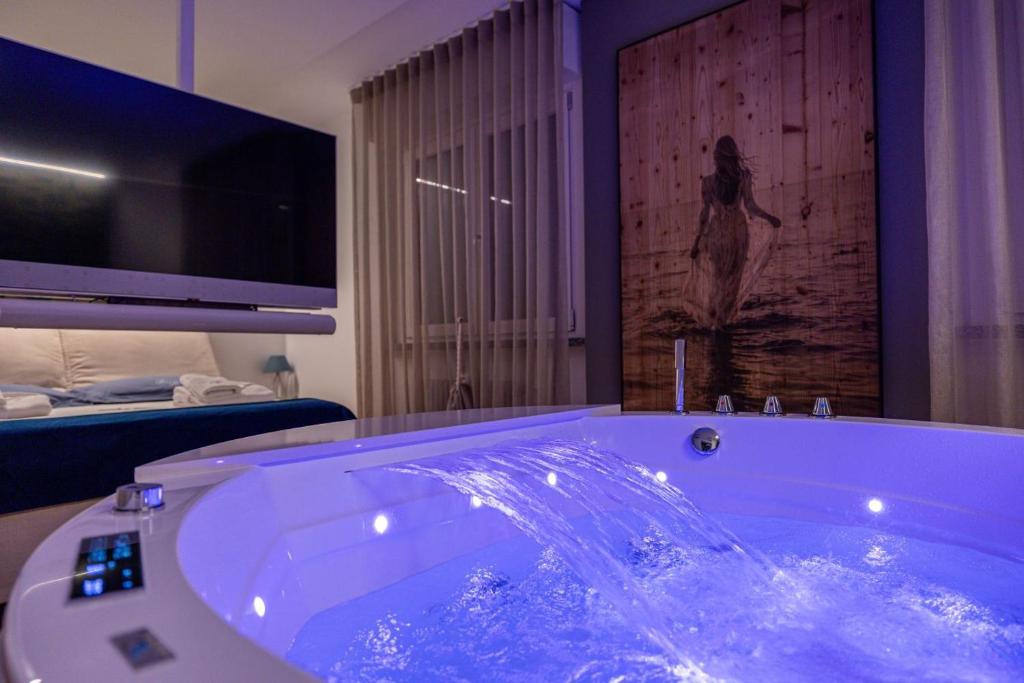 a bathroom with a large tub with a television and a bed at Bed&Dreams con Jacuzzi in Bergamo