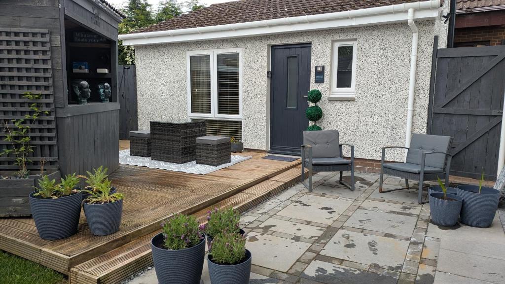 a patio with chairs and potted plants in front of a house at Harestanes Hideaway in Kirkintilloch