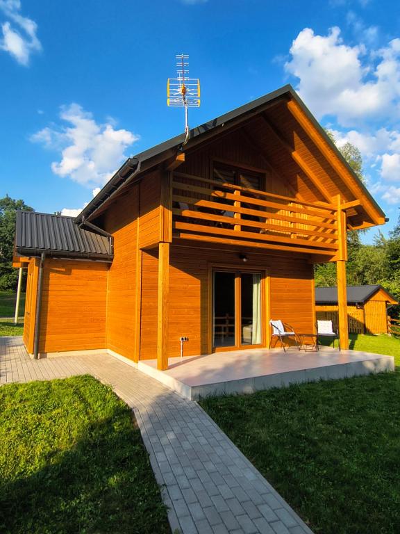 a small wooden house with a patio in the yard at Domek Góra Gbura in Ulucz