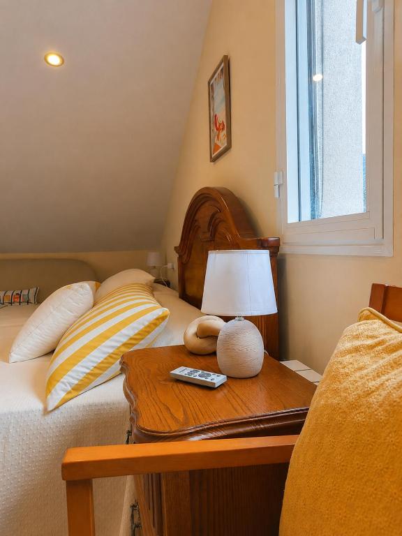 a bed with a table with a lamp on it at Apartamento Duplex con jardín A Casiña de Divina in Lago