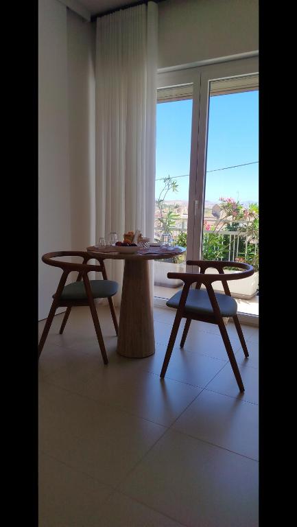 a table and two chairs in a room with a window at Camere DOMOVIEW- design con vista su Cammarata in San Giovanni Gemini