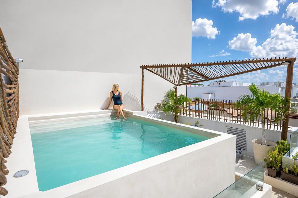 a woman sitting on the edge of a swimming pool on a building at Aruma Suites in Playa del Carmen