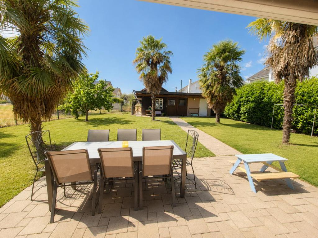 a table and chairs on a patio with palm trees at La maison IDEL in Yvonand