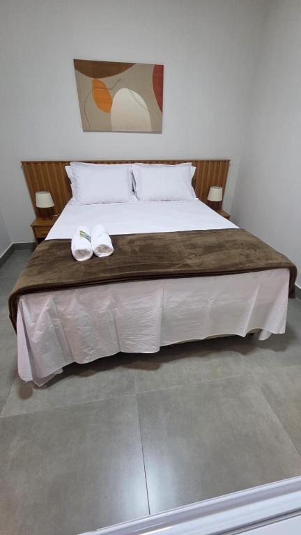 a large bed with two white shoes on it at Lagoa Suítes in Lagoa Santa