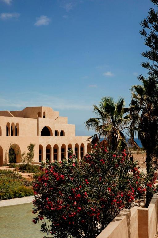 a building with a bush with red flowers in front of it at Nômade Temple Ibiza - New Opening in Portinatx