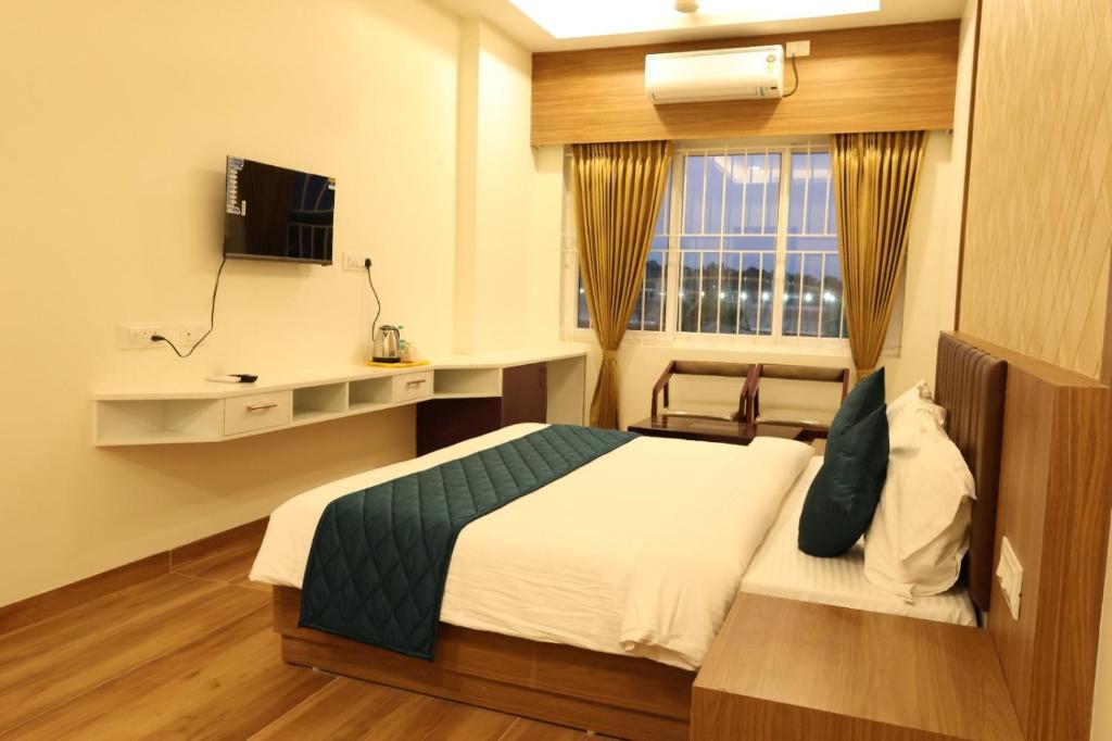 a hotel room with a bed and a window at Skvr Grand in Theni