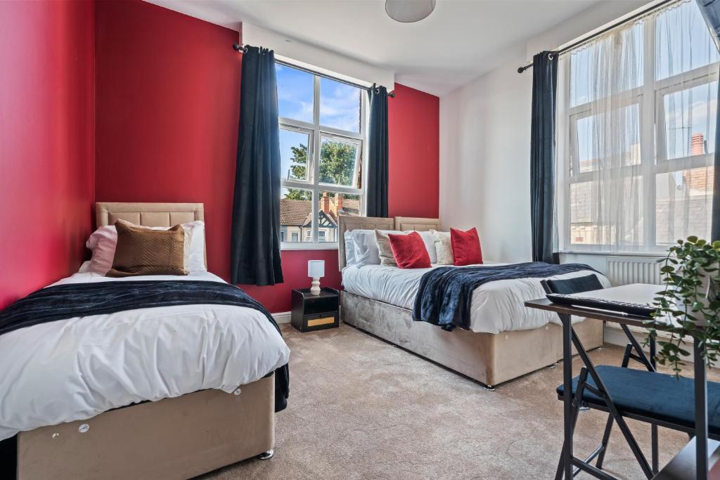 two beds in a room with red walls at The Churchill Hotel in Coventry