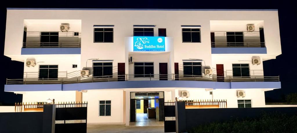 a white building with a blue sign on it at Niru Buddha Hotel, Lumbini in Rummindei