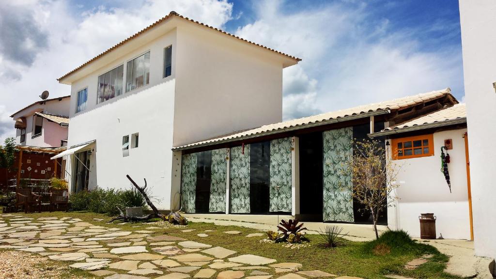 a white house with large windows and a stone driveway at Villa Di Antonio in Tiradentes