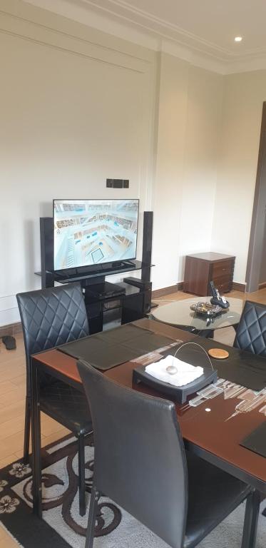 a living room with a table and a flat screen tv at Mzuri Homes in Kampala