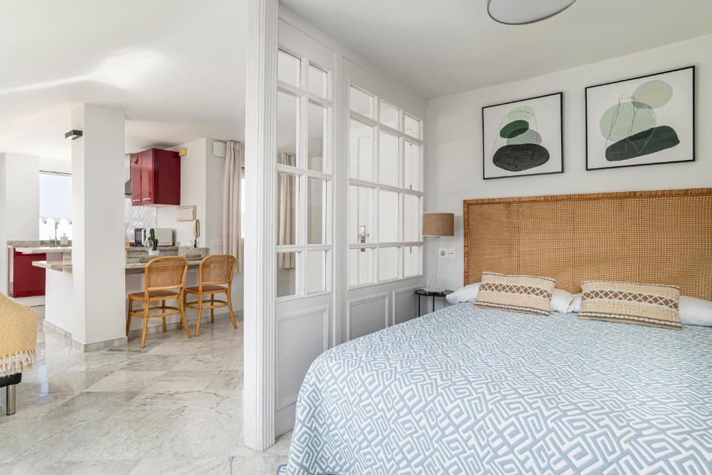 a white bedroom with a bed and a kitchen at Ático Pedro Romero in Ronda