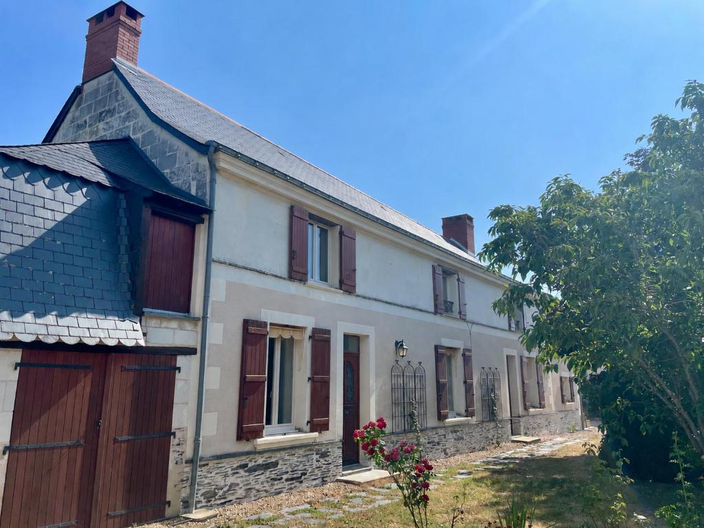 an old white house with brown doors and a fence at Le Logis du pic vert in Saint-Mathurin