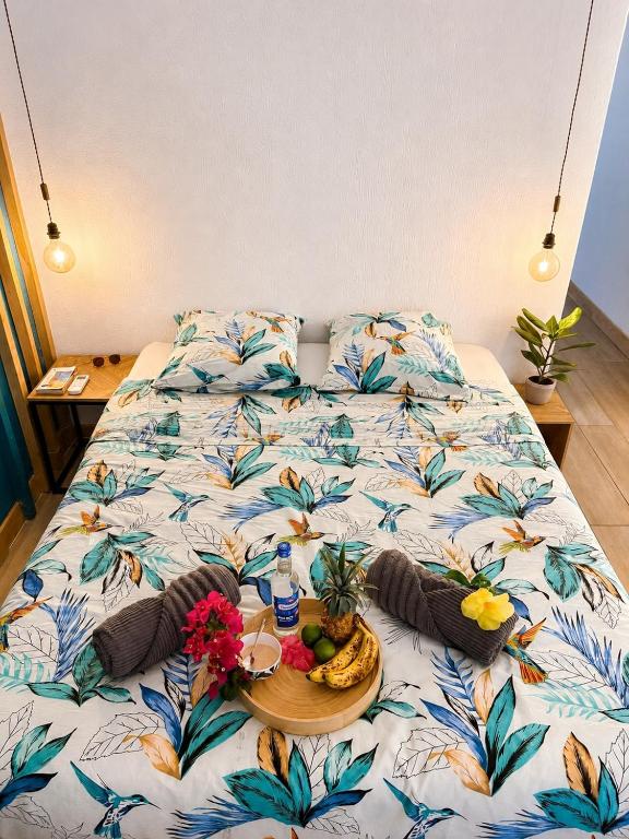 a bed with a tray of food and fruit on it at Reflet Marin - Studio Village Soleil in Le Gosier