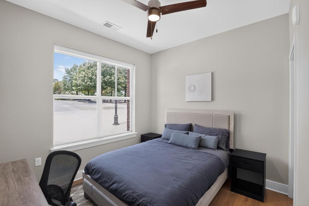 a bedroom with a bed with a ceiling fan and a window at Parkview Greer 2BR Retreat in Greer