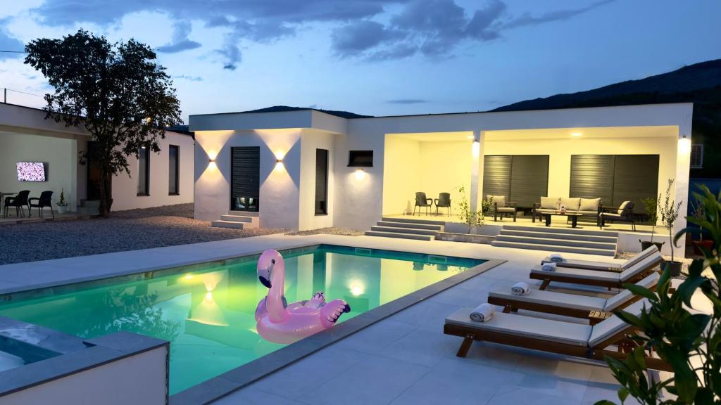 a swimming pool with a pink flamingo in front of a house at Villa Maja in Blagaj