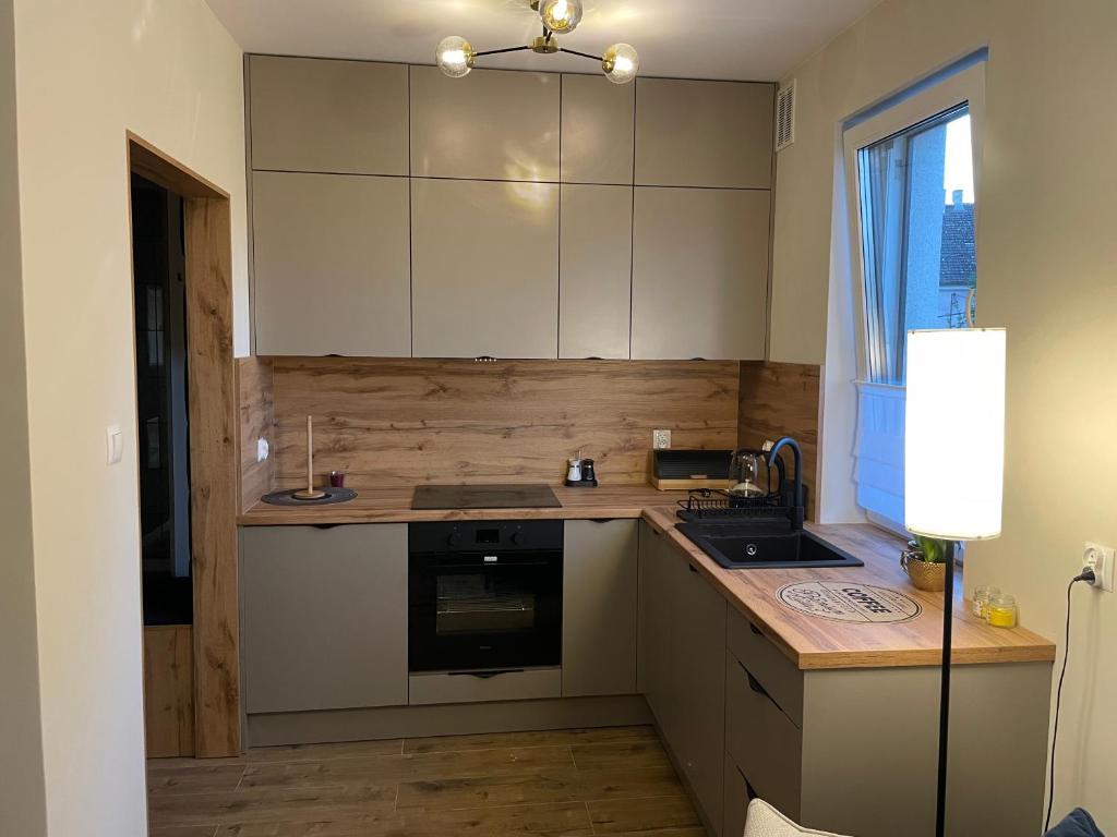 a kitchen with white cabinets and a sink and a window at Apartament Żurawie in Jastrowie