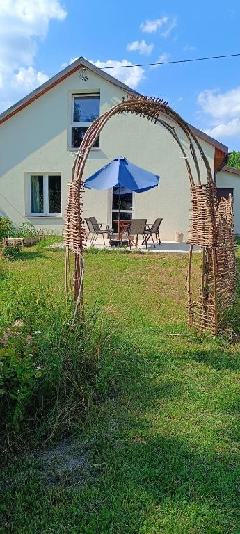 a wicker arch in a yard with a table and an umbrella at Agroturystyka Stasin in Trojanów