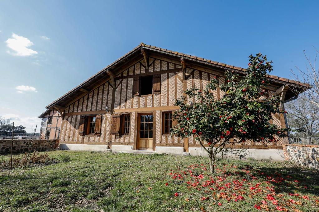 a wooden house with a tree in front of it at Location Le Penan in Léon