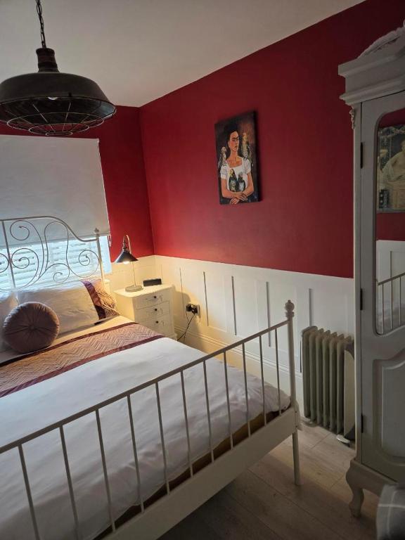 ein Schlafzimmer mit einem Bett und einer roten Wand in der Unterkunft Firefly Studio in Holt