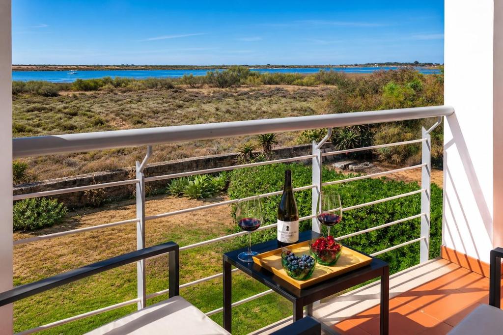 a table with a bottle of wine on a balcony at Bela Ria Waterfront House Pool & Boat to Beach in Cabanas de Tavira