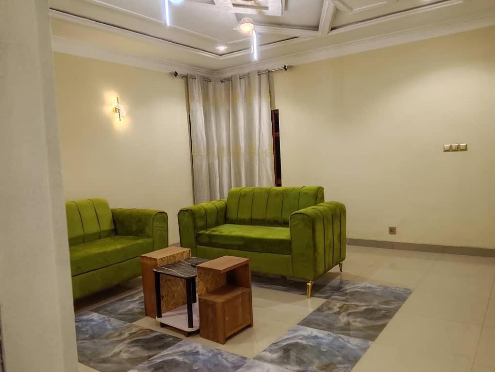 a living room with two green chairs and a table at Maisonnette KF Golf-Self Catering Apartments in Lubumbashi