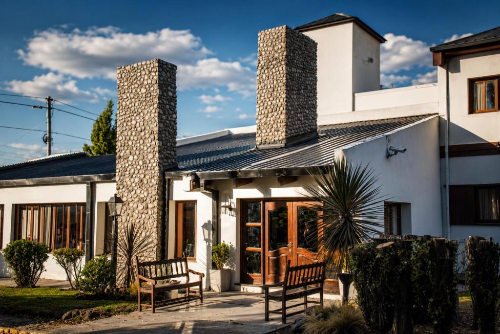 a house with two benches in front of it at Kalken Hotel by MH in El Calafate
