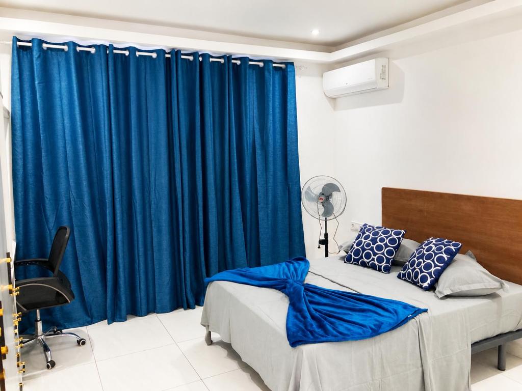 a bedroom with a bed with blue drapes at Mags GuestHouse in Praia