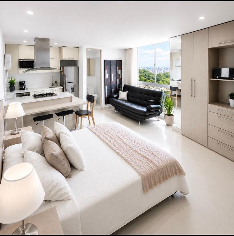 a white bedroom with a large bed and a kitchen at Loft Premium El Poblado in Envigado