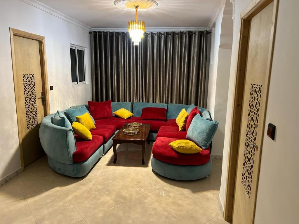 a living room with a red couch and yellow pillows at Atouli Suites in Nador