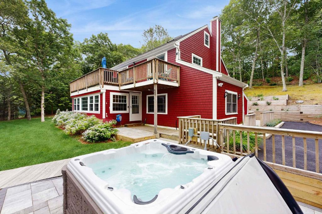 a red house with a hot tub in the yard at Pond Treasure in Sandwich
