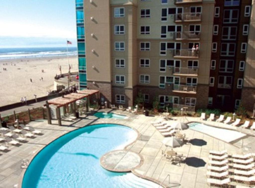 a view of a hotel with a swimming pool and a beach at Seaside Ocean Front Condo in Seaside