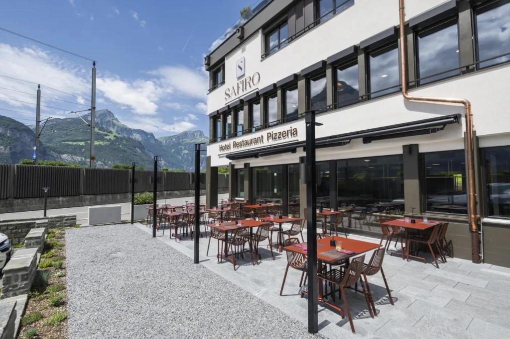 a restaurant with tables and chairs outside of a building at Hotel Safiro in Fluelen