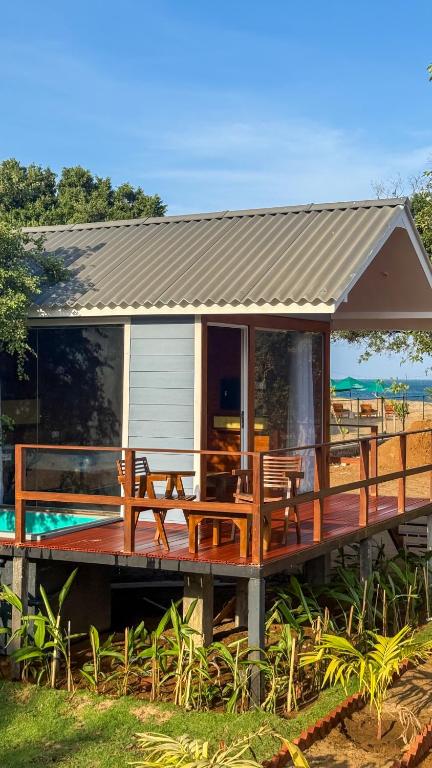 a house with a deck with a table and chairs at Leopard Inn Arugam Bay in Arugam Bay