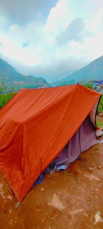 an orange tent sitting on top of a dirt field at Glacier view point kedarnath in Kedārnāth
