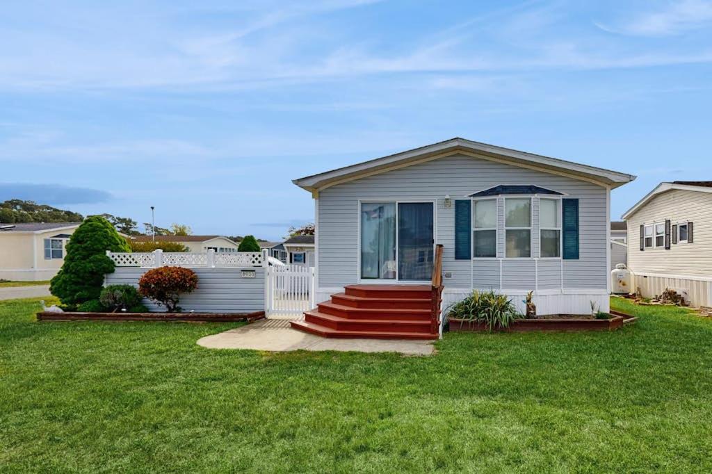a small house with a red staircase in a yard at Assateague Point - Bay Breeze in Berlin